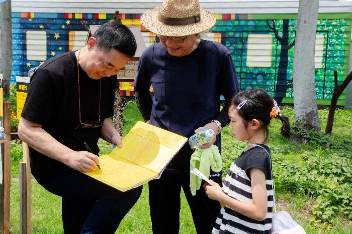 大地の芸術祭で作家のジミーリャオさんにサインをもらう少女