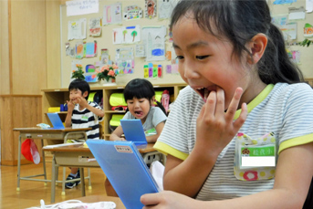 歯の健康を確認するために鏡に向かい口を開いて指で歯を触っている女子小学生