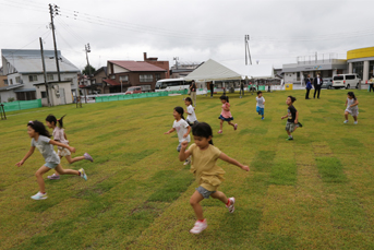 芝生の上を大勢の保育園児が走り回っている