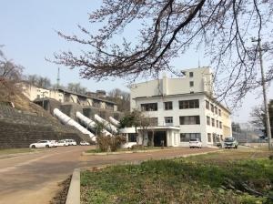 白い建物が丘の上に建っている、千手発電所の写真
