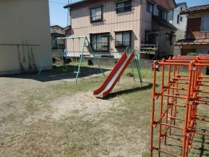 宮本公園の、橙と緑の色合いのジャングルジムとすべり台、ブランコの写真