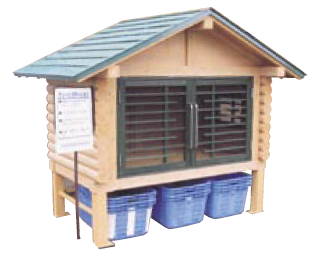 看板とかごが用意された、小屋型のごみステーションの写真