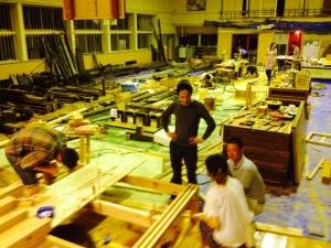4人の男性が、沢山のテーブルを制作している処の写真