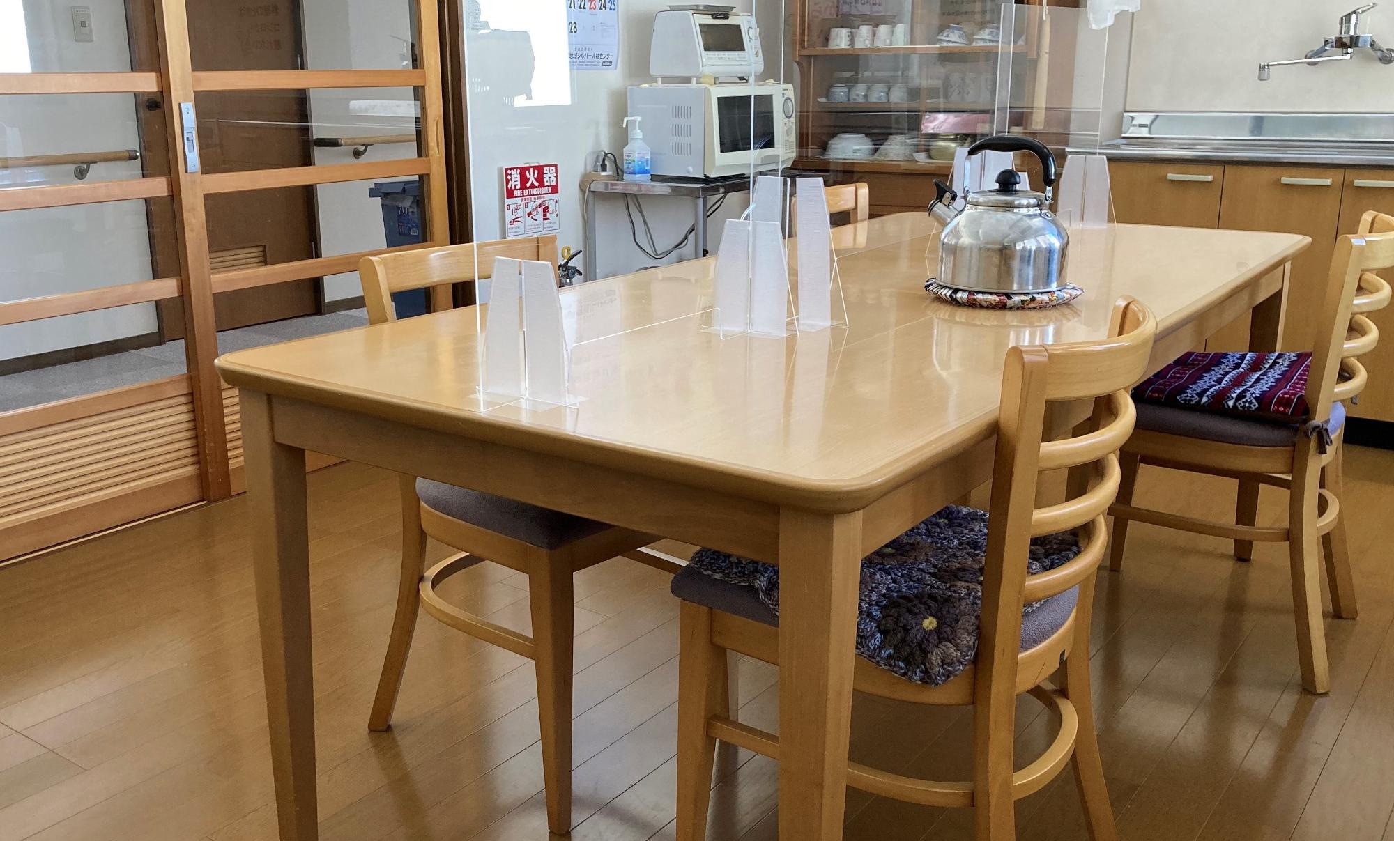 中央奥に調理器具、右奥にシンク、手前にテーブルと4つのイスがある共用キッチンの写真