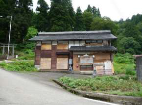 坂道につながる茶色の2階建て一軒家の写真