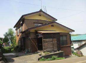 玄関までに緩やかな坂のある2階建て木造一軒家の写真