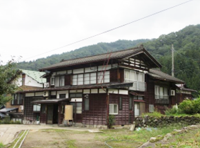 石垣のある濃い茶色の木造2階建て一軒家の写真