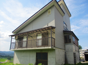 コンクリート壁のガレージ付き白い2階建て一軒家の写真