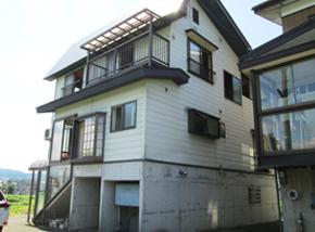 コンクリート壁ガレージのある白い2階建て一軒家の写真