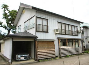 ガレージ付きの白い2階建て一軒家の写真
