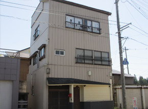 1階がガレージの薄茶色の3階建て一軒家の写真