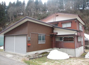 ガレージ付きの茶色い2階建て一軒家の写真