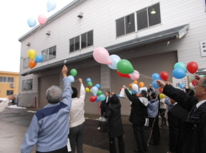色とりどりの風船を空に放つ関係者たち。