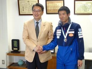 互いに握手を交わして記念撮影に応じる市長と村越選手の写真