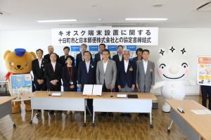 協定書締結式にて記念撮影に応じる市長と青木代表および役員たちの集合写真