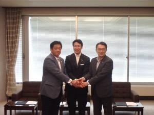 協定書締結後、握手を交わす三者の写真