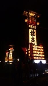 夜の街中を練り歩く巨大なキリコの写真
