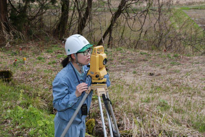 トータルステーションを用いて測量を行う池田さんの写真