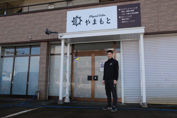 ご自分の店舗の前で撮影をしている山本さんの写真