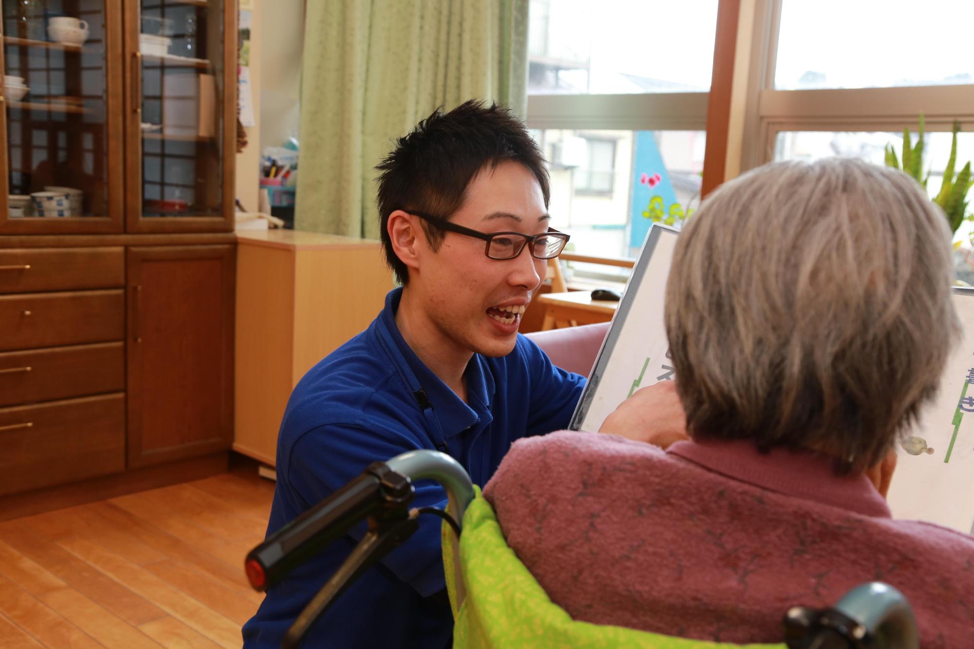 利用者の方に明るい表情で語りかける金子恭平さんの写真