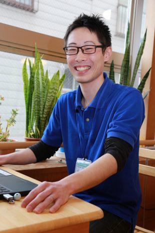 椅子に座っている笑顔の金子恭平さんの写真