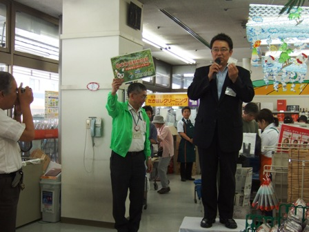 店内の壇上で市長が挨拶している。