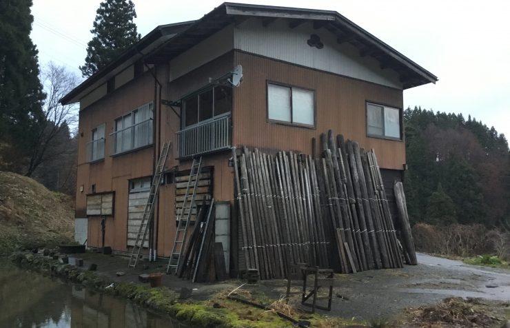 正面が木の板に覆われた茶色い2階建て一軒家の写真