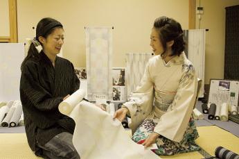 出来上がった布を触って喜んでいる様子の着物を着た女性の写真