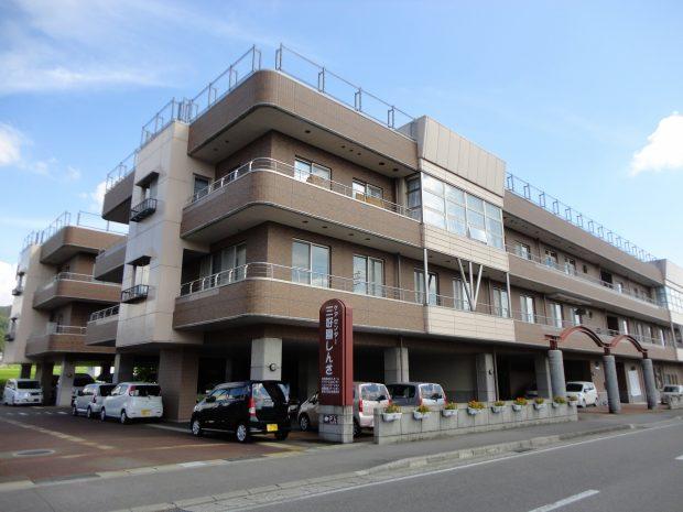 看板とともに撮影されたケアセンター 三好園しんざの外観写真