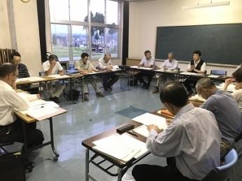 ロの字に並べられた机の前に置かれた椅子に座り、会議に参加する人々の写真