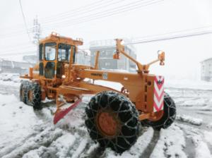 除雪グレーダーが固くなった雪を剥がしながら除雪している様子の写真