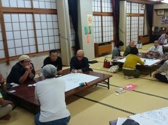 畳の上に置かれたいくつかの机の前に座り、会議に参加する人々の写真