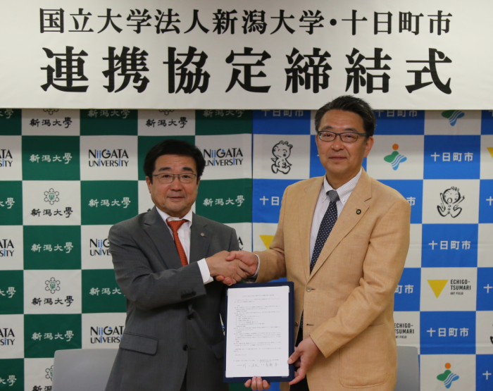 新潟大学連携協定締結式で握手している市長と新潟大学の高橋学長の写真