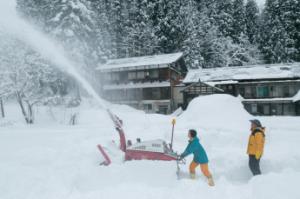 庭で大活躍している小型除雪機の様子を楽しんでいる親子の写真
