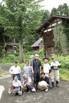 外で地域おこし協力隊員がスコップや鎌などを持ち並んでいる写真