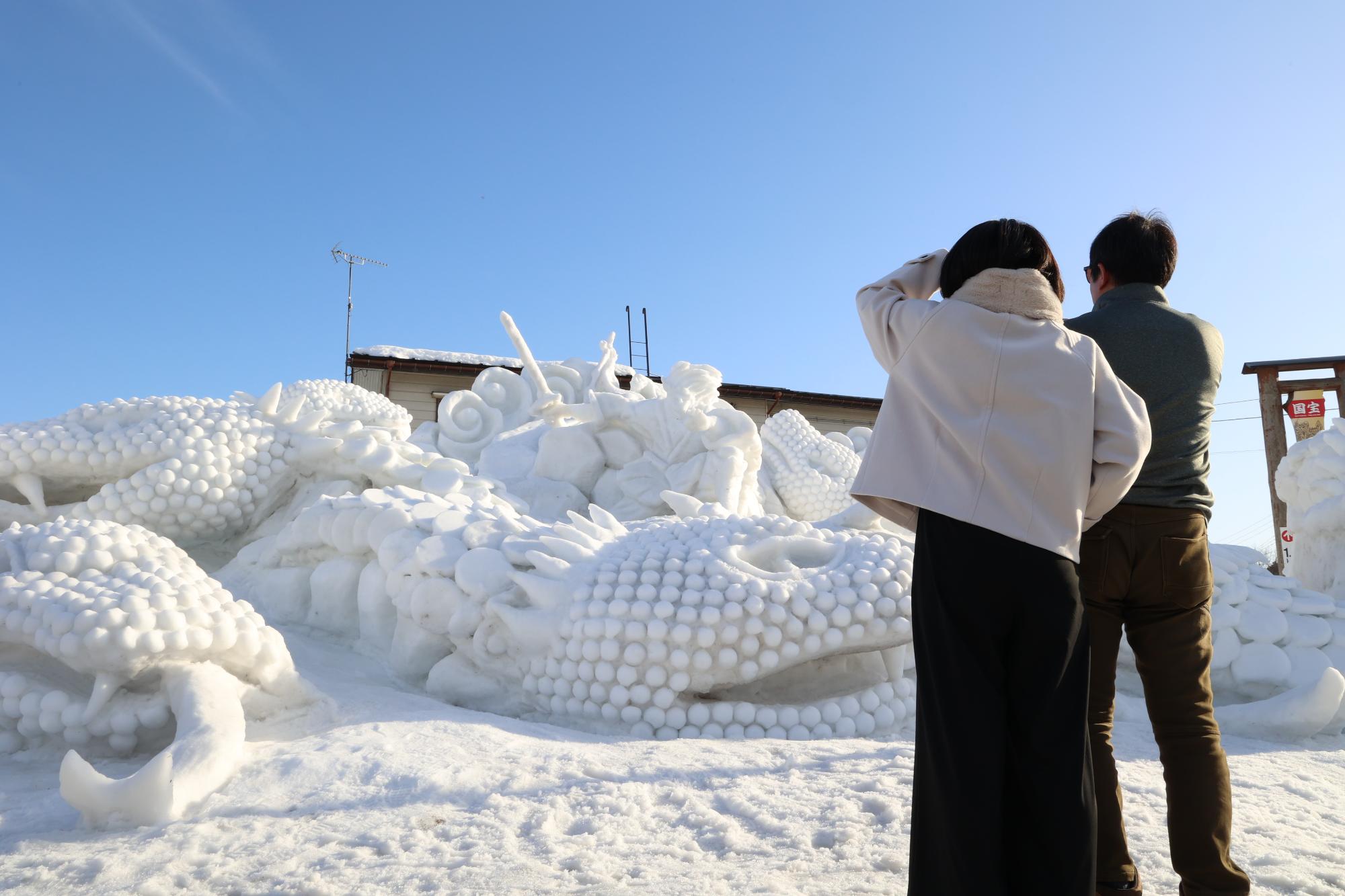 十日町雪まつりにおける芸術的な雪像を眺める人を収めた写真