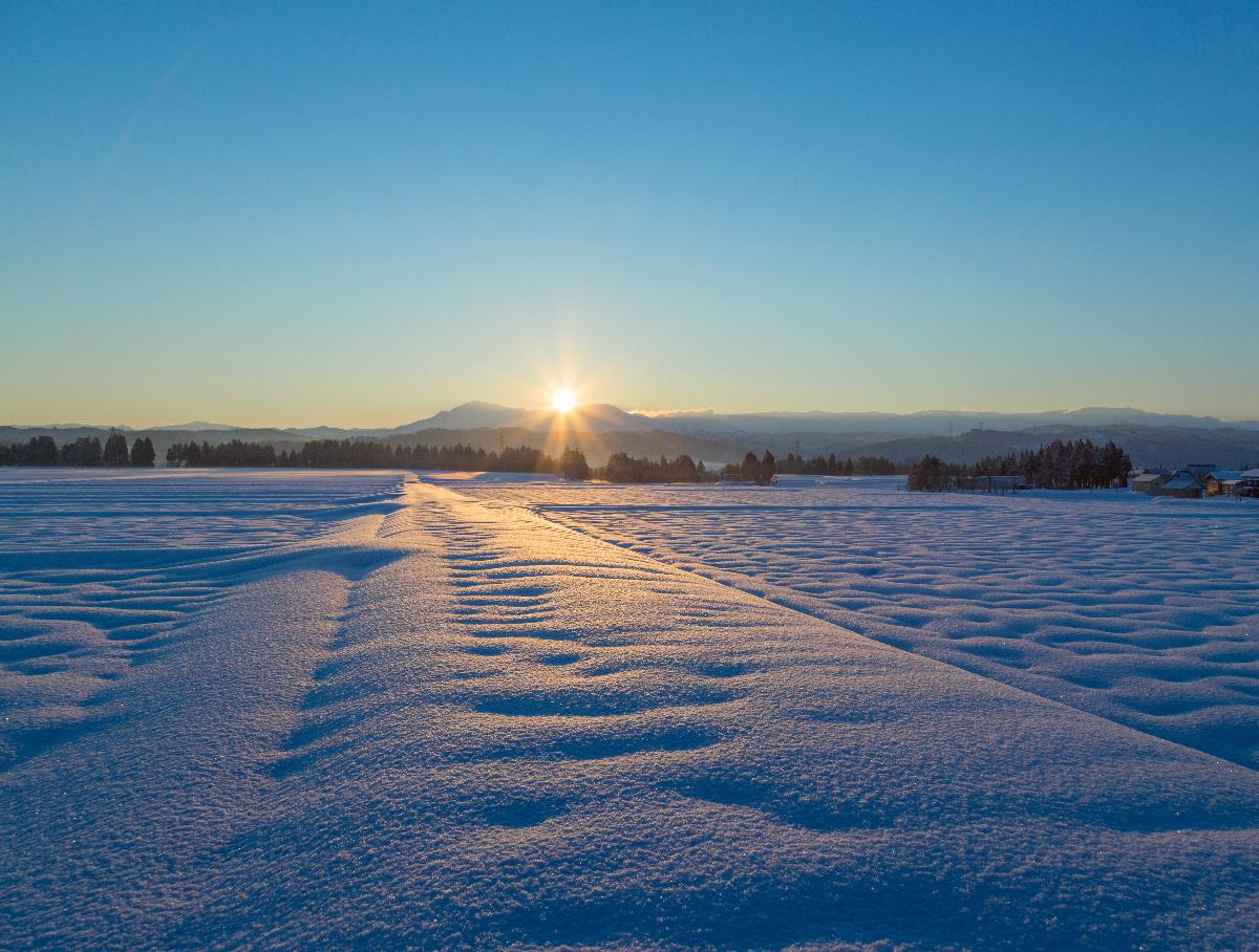 一面に広がる雪景色の中朝日が昇る風景