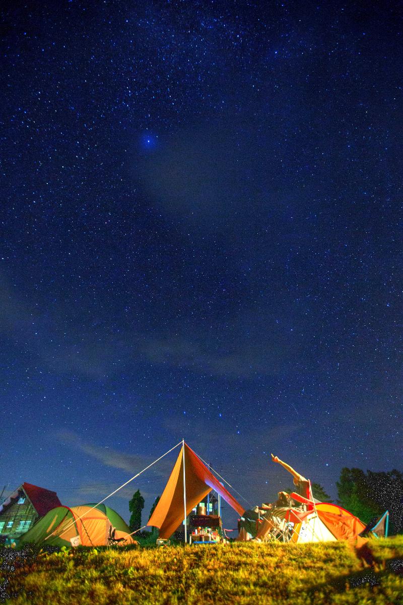 キャンプをしている人が満点の星空を見上げている様子