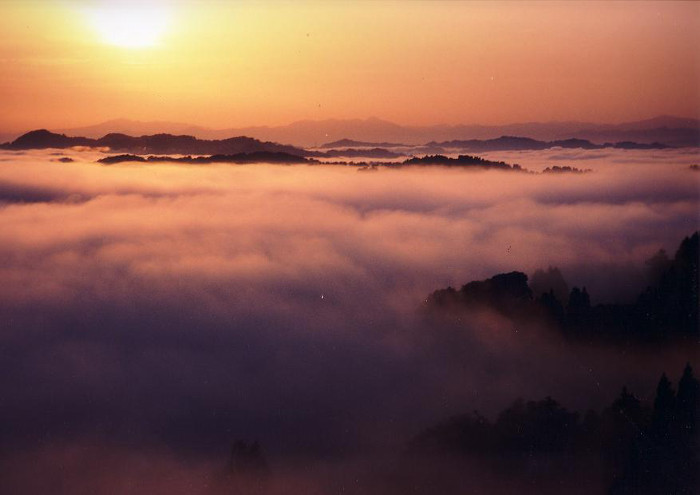 朝日が昇る中一面の雲海が山々を覆う雄大な景色