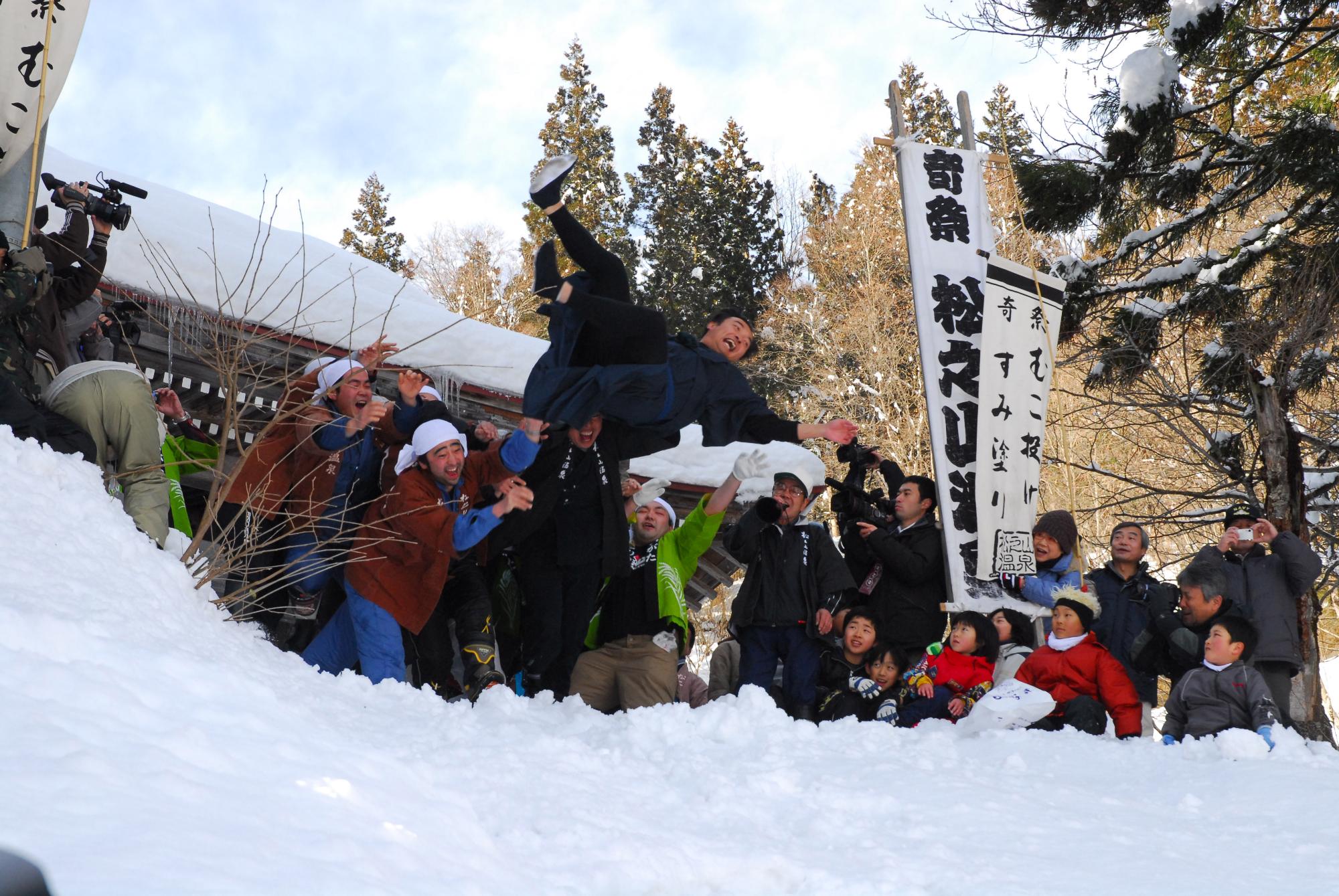 胴上げされた男性が雪の中に投げられる様子