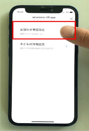 スマホ画面上に表示されている「お知らせ受信設定」を指差している