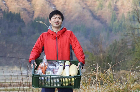 野菜がたくさん入っている籠を両手で持ち上げる男性