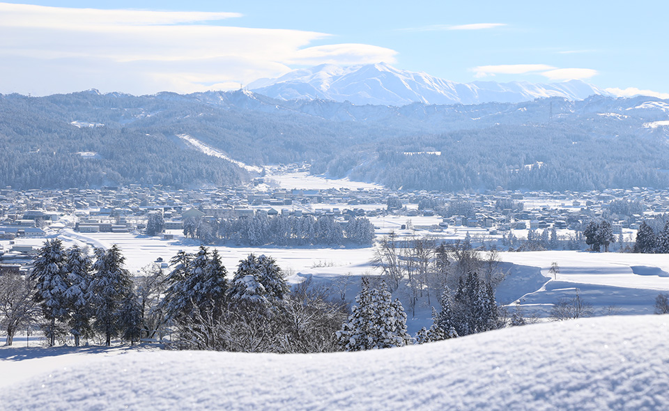 吉田地域から眺める十日町市街地の雪景色。奥には越後三山を望む