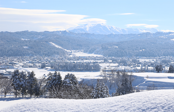吉田地域から眺める十日町市街地の雪景色。奥には越後三山を望む。