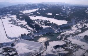 雪が積もった地面に囲まれた、浅河原調整池を上空から撮影した写真