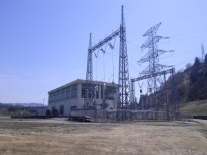 草地の中に、様々な鉄塔がある小千谷第二発電所が建っている写真