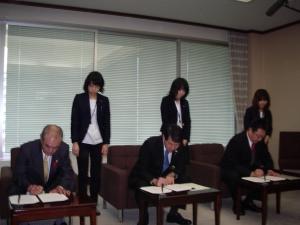 知事、両市長による協定書への署名の様子を撮影した写真