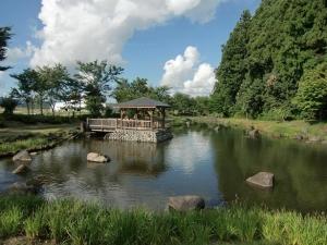 大井田の郷公園の岩が点在する池と島に建っている東屋の写真
