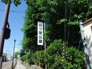 生い茂る木々を背景にして立つ四ツ宮公園の看板の写真