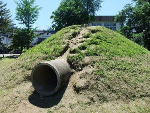 公園南側に設けられた、土管の突き出た築山の写真